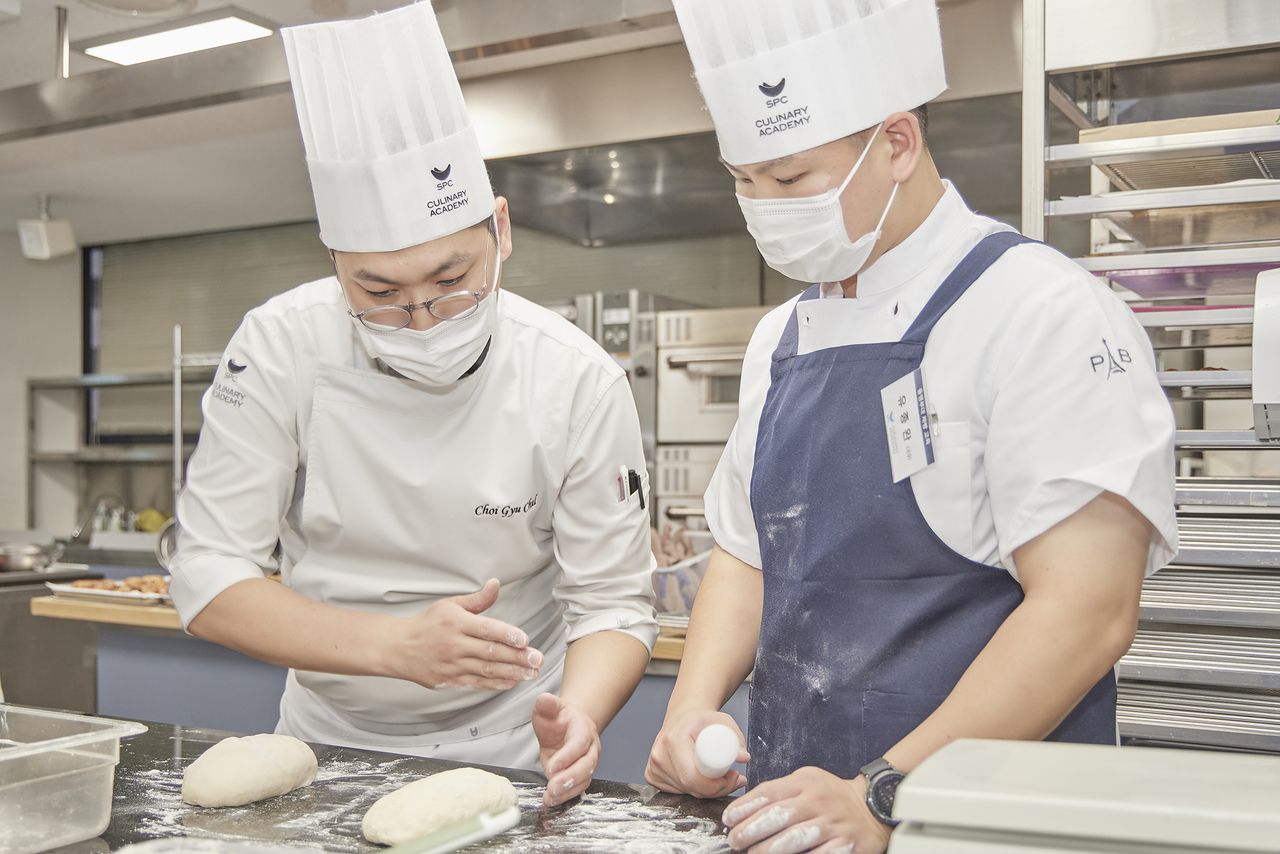 An SPC instructor works with a soldier during a baking and pastry training program at the SPC Culinary Academy in Seoul. (SPC Group)