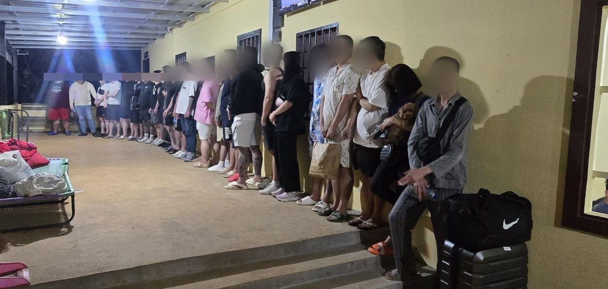 Suspected South Korean phishing scammers arrested by a Korea-Cambodia joint task force wait to be transported at a crime compound near the Cambodia-Vietnam border on Dec.18. (Korean National Police Agency)