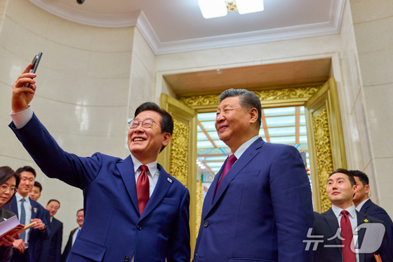  President Lee Jae Myung and Chinese President Xi Jinping pose for a commemorative photo with the Xiaomi smartphone presented to them during last November\'s summit in Gyeongju after concluding a state banquet at the Great Hall of the People in Beijing on Monday. 2026.1.5 / News1