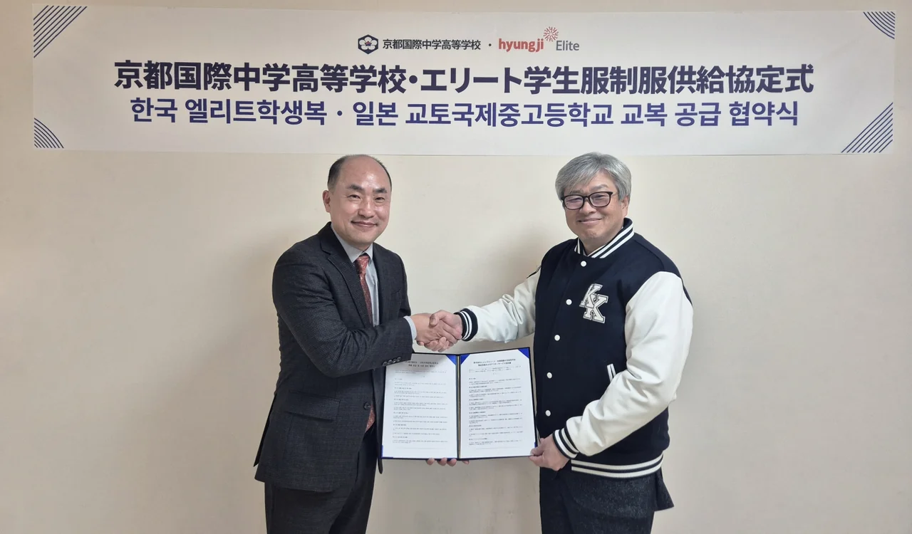 Hyungji Elite Executive Director Nam-yong Kim (left) and Kyoto International Middle and High School Chairman Jung-hong Kim (right) exchange the agreement and shake hands at the uniform supply contract signing ceremony. / Photo courtesy of Hyungji Elite.