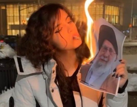 한 젊은 여성이 이란 최고 지도자 아야톨라 세예드 알리 하메네이 사진을 불태워 담뱃불을 붙이는 모습. ⓒ 엑스(X) 캡처