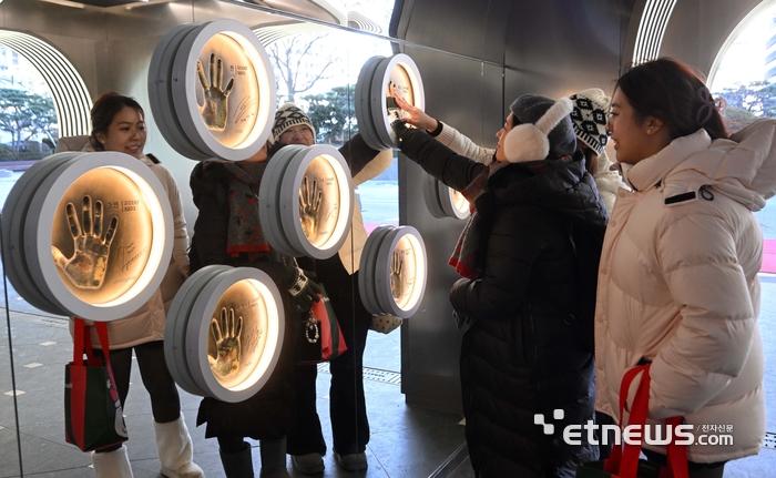 한한령 해제와 방한시장 확대에 대한 기대감이 커지는 가운데 유통가가 외국인 관광객 유치를 위한 새단장에 나섰다. 13일 서울 중구 롯데면세점 스타에비뉴에서 관광객이 K팝 스타들과 손을 맞춰볼 수 있는 '스타 하이파이브'를 체험하고 있다. 김민수기자 mskim@etnews.com