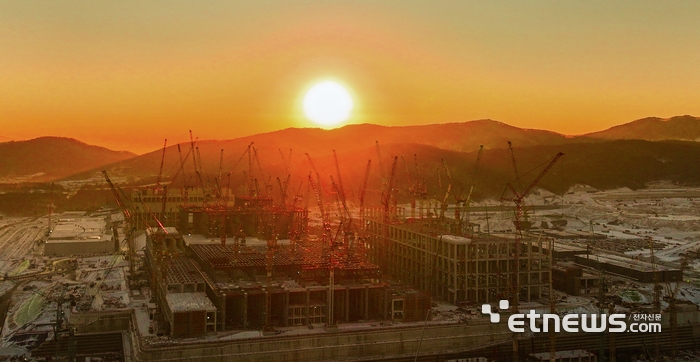 붉은 말의 해 병오년(丙午年), 거침없는 도약과 활력을 상징하는 기운 속에서 대한민국 반도체 산업이 새로운 출발선에 섰다. 경기도 용인시 SK하이닉스 용인 클러스터 1기 팹 건설 현장에 붉은 기운을 머금은 태양이 수십 대의 대형 크레인 너머로 떠오르고 있다. 차세대 고대역폭메모리(HBM)를 비롯한 AI 핵심 반도체를 생산할 이곳은 한국형 AI 경쟁력의 전진기지로, 대한민국이 'AI 3대 강국'으로 도약하기 위한 중요한 이정표가 될 전망이다. 용인=이동근기자 foto@etnews.com