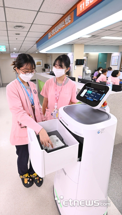 대형병원 등 의료현장에 의료서비스로봇 도입으로 의료진 업무 효율과 환자 만족도가 높아지고 있다. 의료서비스로봇은 의약품 및 검체운반, 병원안내, 병동 간 물품 배송, 환자교육 등 간호·진료 지원 업무에 활용되고 있다. 5일 총 11종 77대의 의료서비스로봇을 활용하는 경기도 평촌 한림대성심병원에서 간호사들이 배송된 약을 받고 있다. 박지호기자 jihopress@etnews.com