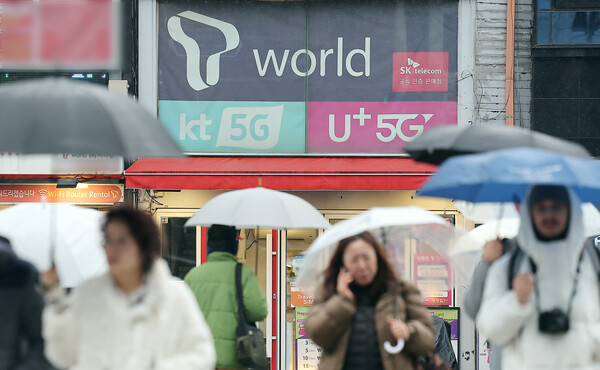 시민들이 2025년 12월 23일 오후 서울의 한 휴대폰 매장 앞을 지나가고 있다. / 뉴스1