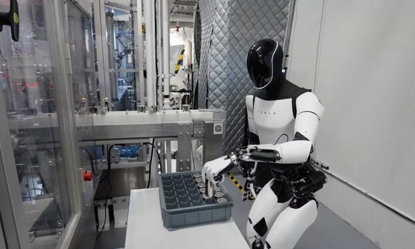 테슬라 옵티머스가 상자 안에서 물건을 들어올리는 작업을 하고 있다 [사진=테슬라]