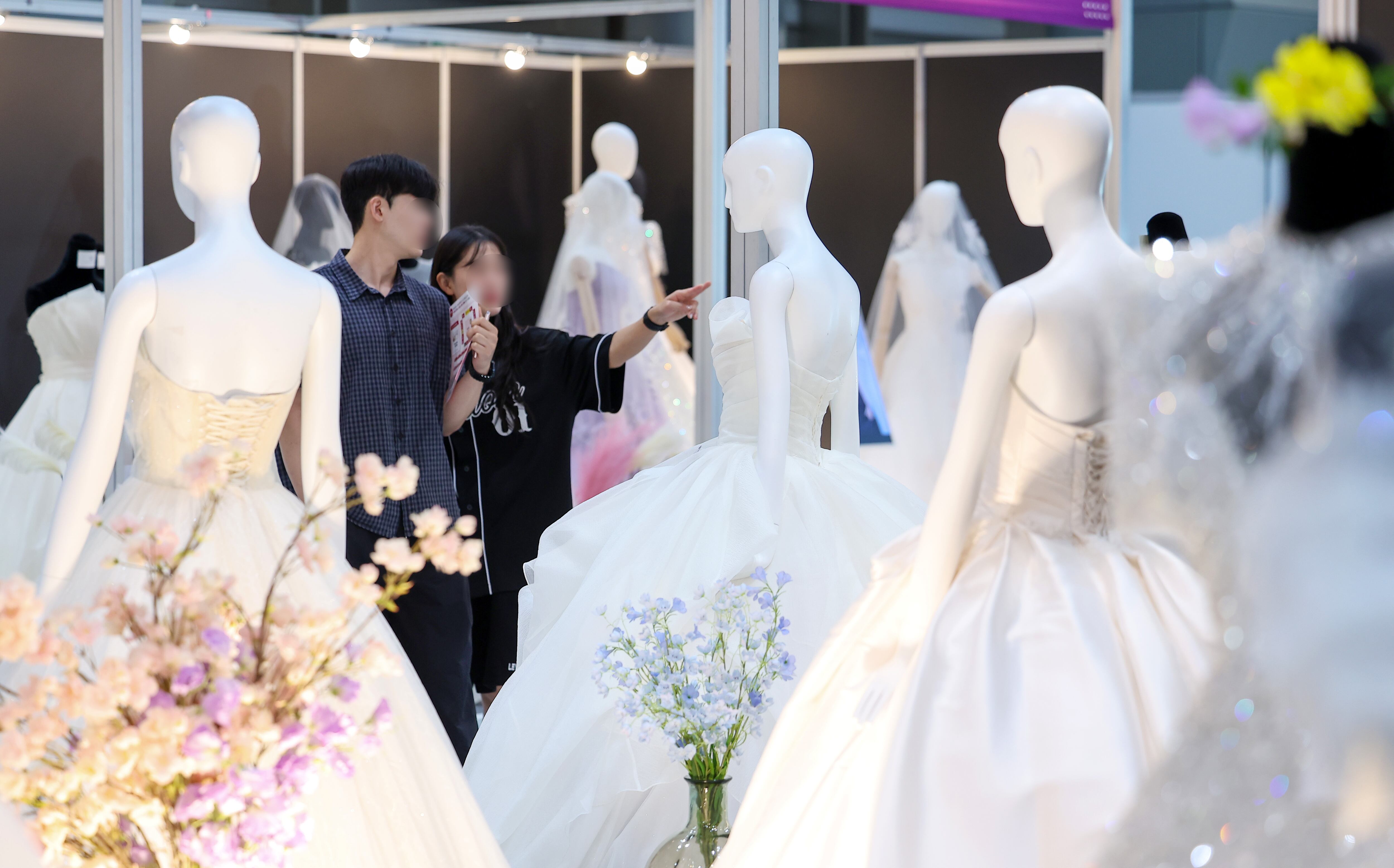 서울 강남구 삼성동 코엑스에서 열린 2025 추계 웨덱스 웨딩 박람회에서 예비 부부들이 전시된 드레스를 살펴보고 있다. /뉴스1