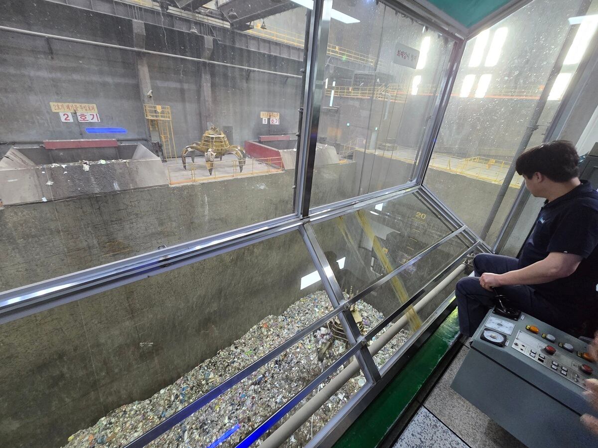 인천 청라소각장 제어실에서 직원이 크레인을 통해 저장조에 쌓인 폐기물을 집어올리고 있다. /뉴스1