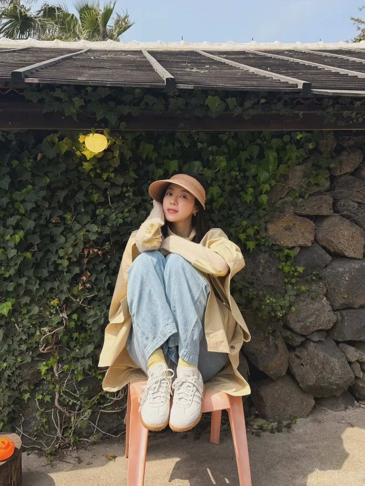 &nbsp;     Park Han-byul finishes off a Jeju spring look with a beige cape coat and a raffia visor, clutching a tangerine. /Photo: Park Han-byul Instagram