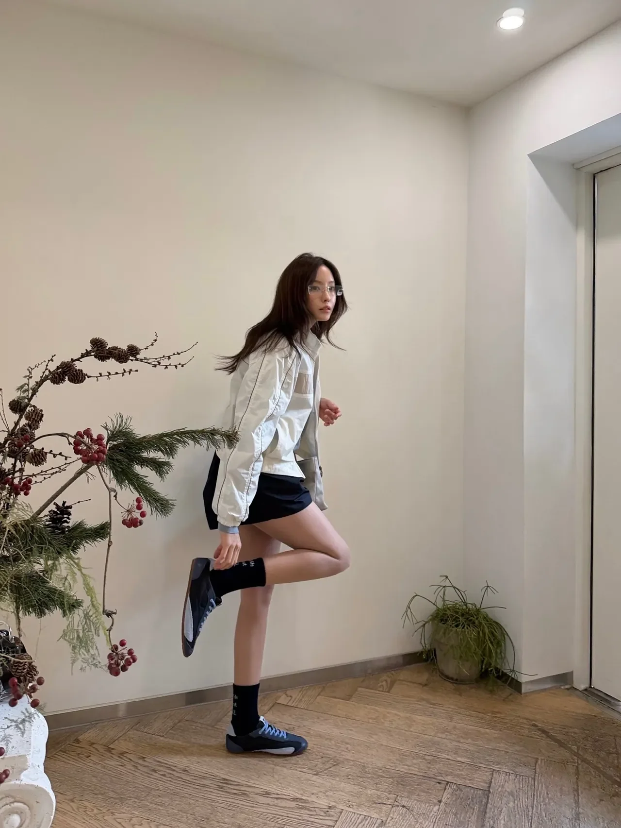 Hyomin takes a mirror selfie in the FILA windbreaker, navy shorts, and a FILA cap. /Photo: Hyomin Instagram