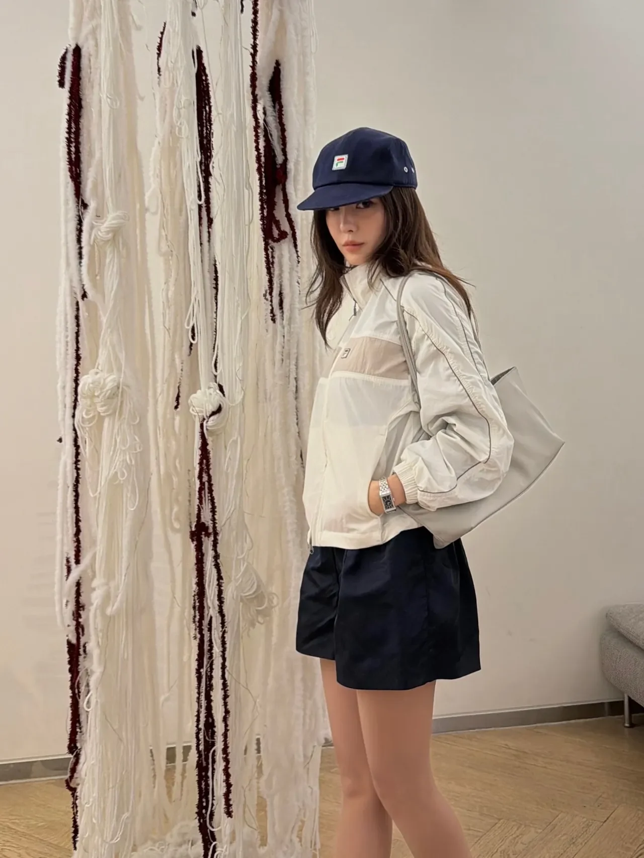 Hyomin shared a mirror selfie showing the FILA windbreaker paired with gray wide-leg pants. /Photo: Hyomin Instagram