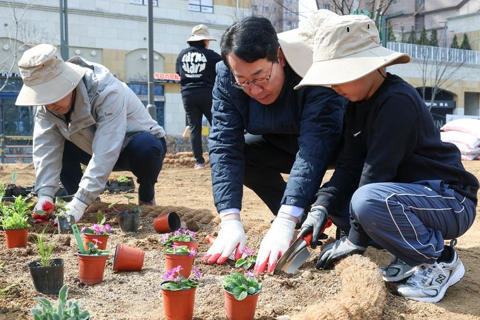 정명근 화성시장이 지난 21일 동탄여울공원에서 화성특별정원에 아이와 함께 꽃을 심고 있는 모습. ⓒ화성시 제공