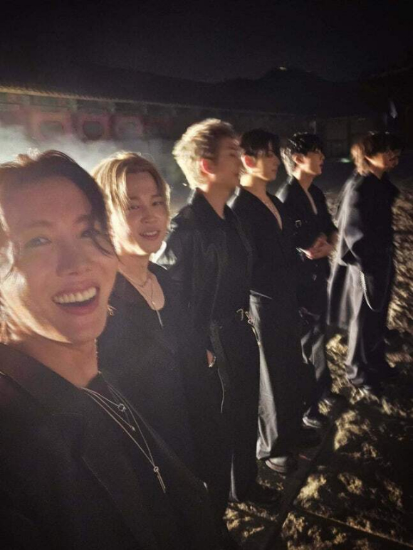 

<figure>” /><figcaption>
<figure></figcaption></figure>
<p>公開された写真には、オールブラックの衣装で屋外撮影をするBTSの姿が写っている。別の写真では練習室で自撮りするジェイホープとジョングクが写っている。</p>
<figure><img decoding=