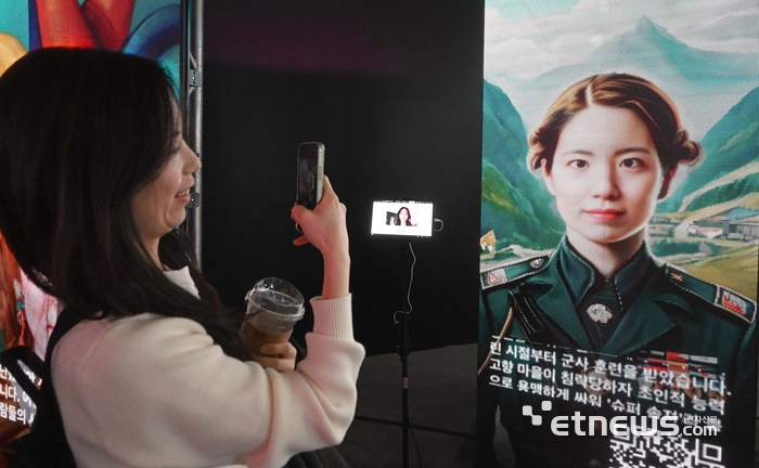 AWS 서밋 서울 엑스포에 마련된 아마존배드록 부스에서 관람객이 생성형AI를 이용해 자신의 얼굴을 그림속 캐릭터와 합성해볼 수 있는 콘텐츠를 체험하고 있다. 김민수기자 mskim@etnews.com
