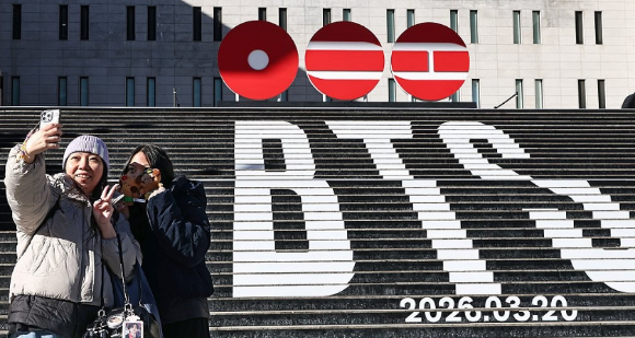 &nbsp;  Tourists from Hong Kong pose with promotional materials announcing BTS’s return as a full group for the first time in three years and nine months. Jan. 22, 2026. [Photo: Yonhap News]