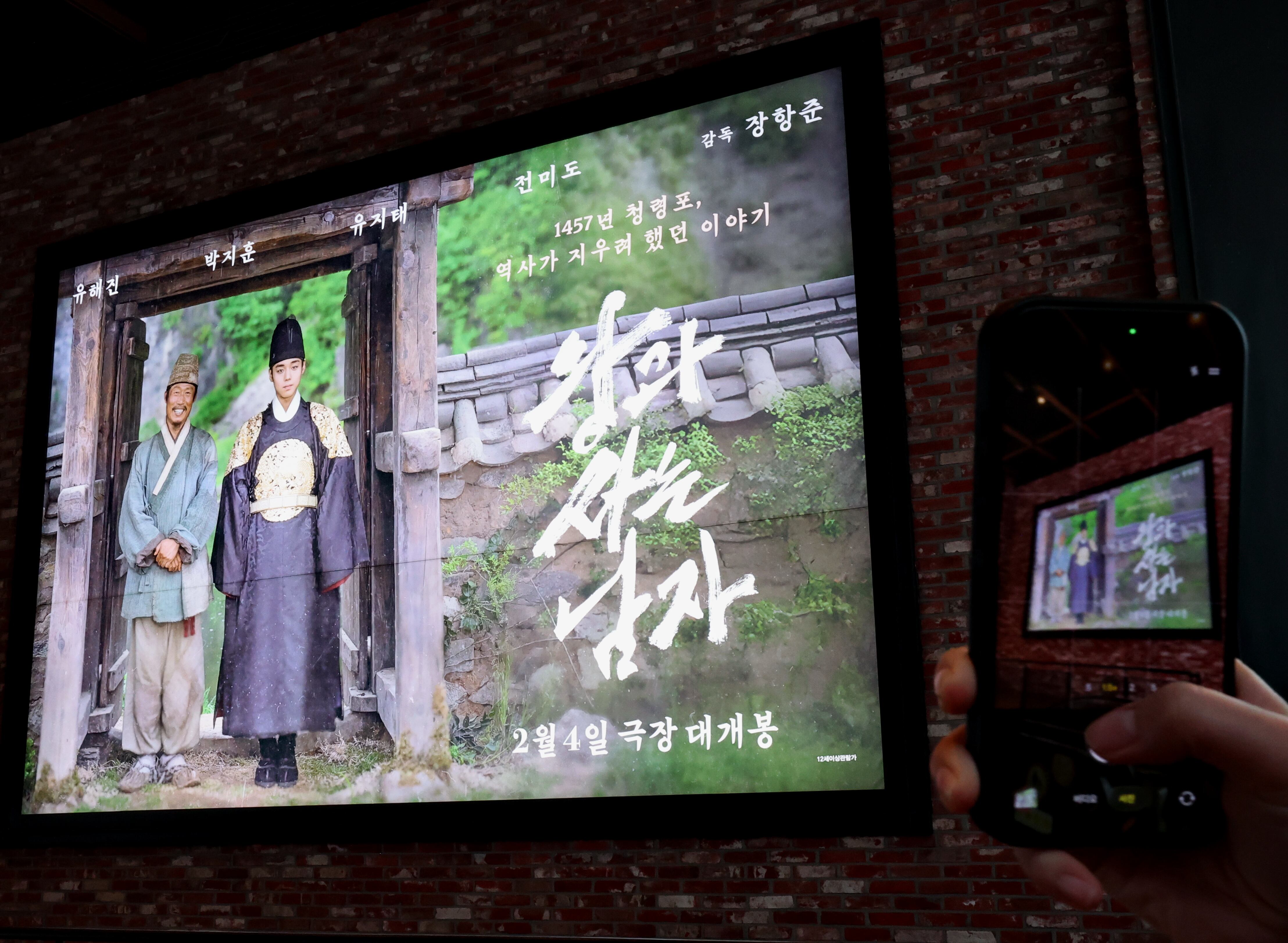 6일 서울 한 영화관에서 시민이 '왕과 사는 남자' 영화 홍보물을 촬영하고 있다. /연합뉴스