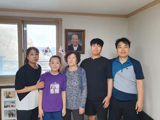 독도의 유일한 주민이었던 김신열(가운데)씨가 경북 울릉군 울릉읍 독도리 서도 주민숙소에서 딸, 사위, 외손자, 손녀와 함께 기념사진을 찍고 있다. 김씨 뒤에는 2018년 숨진 남편 김성도씨 사진이 걸려 있다. /연합뉴스