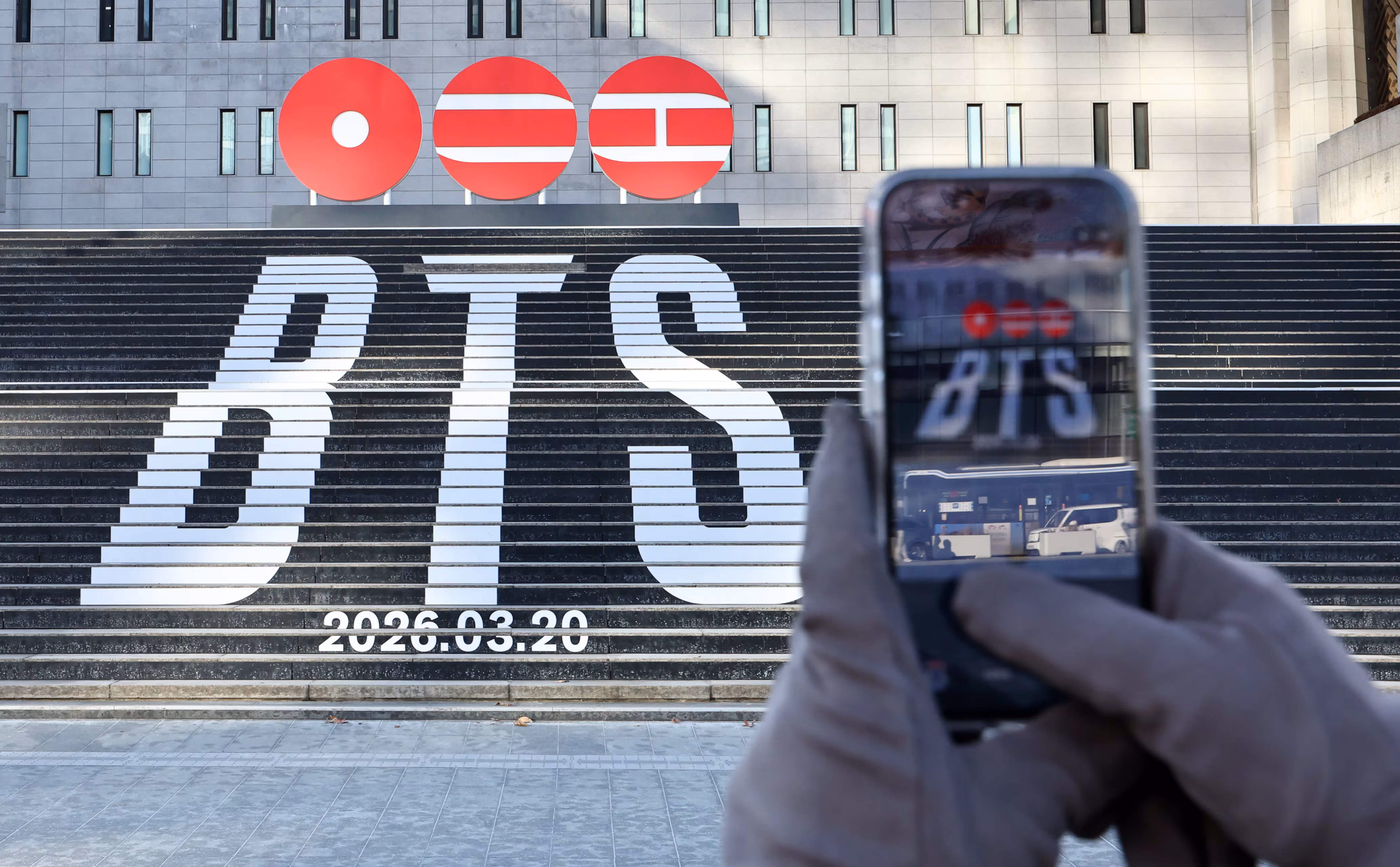 세종문화회관 계단에 설치된 방탄소년단(BTS)의 정규 5집 컴백을 알리는 홍보물을 배경으로 관광객들이 기념촬영을 하고 있다. /뉴스1