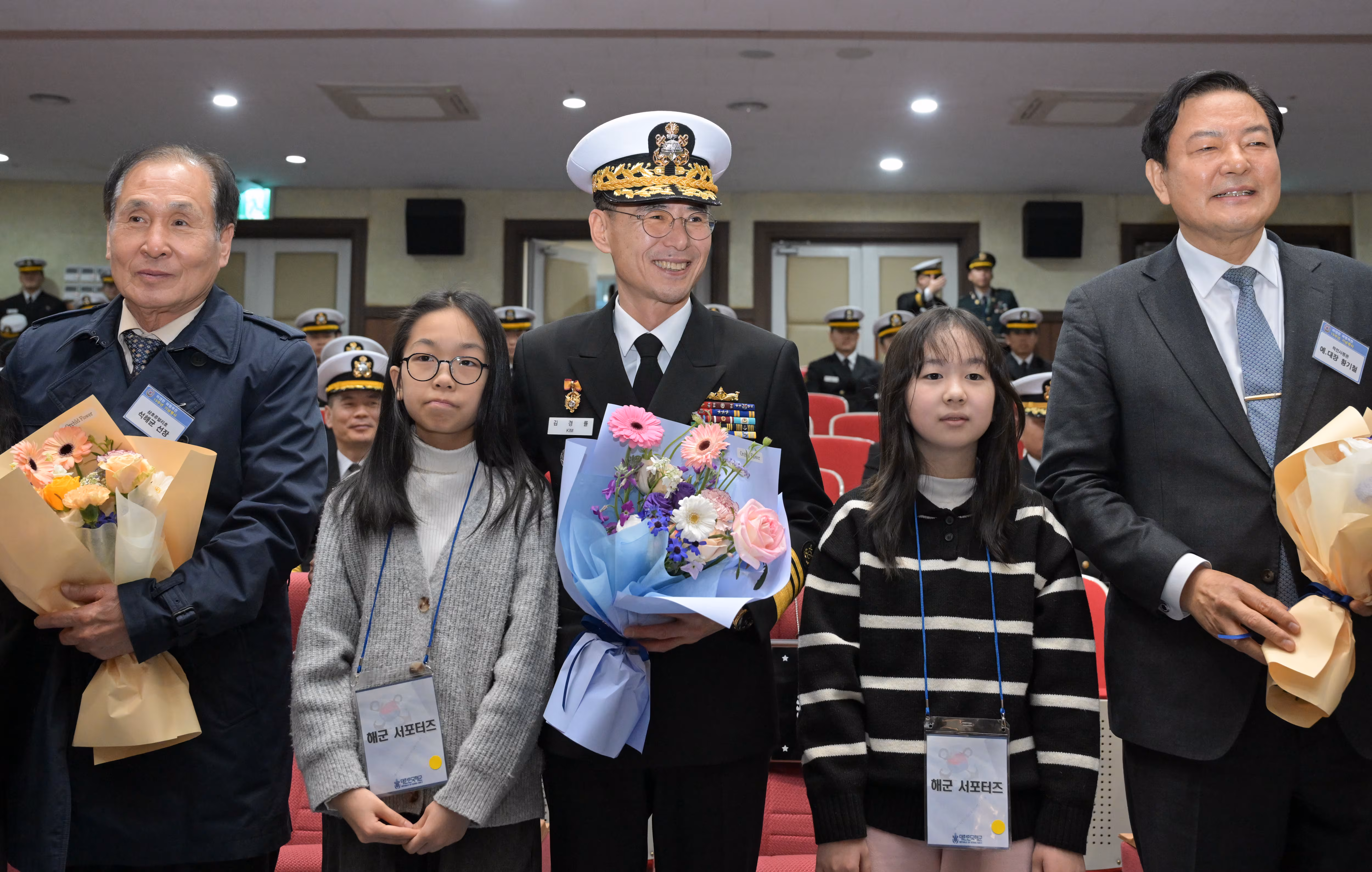  부산 남구 해군작전사령부에서 열린 제15주년 아덴만 여명작전 기념행사에서 김경률(가운데) 해군작전사령관, 석해균 삼호주얼리호 선장, 당시 해작사령관이었던 황기철 전 참모총장이 해군서포터즈 학생들로부터 꽃다발을 받고 기념촬영을 하고 있다. /해군작전사령부 제공