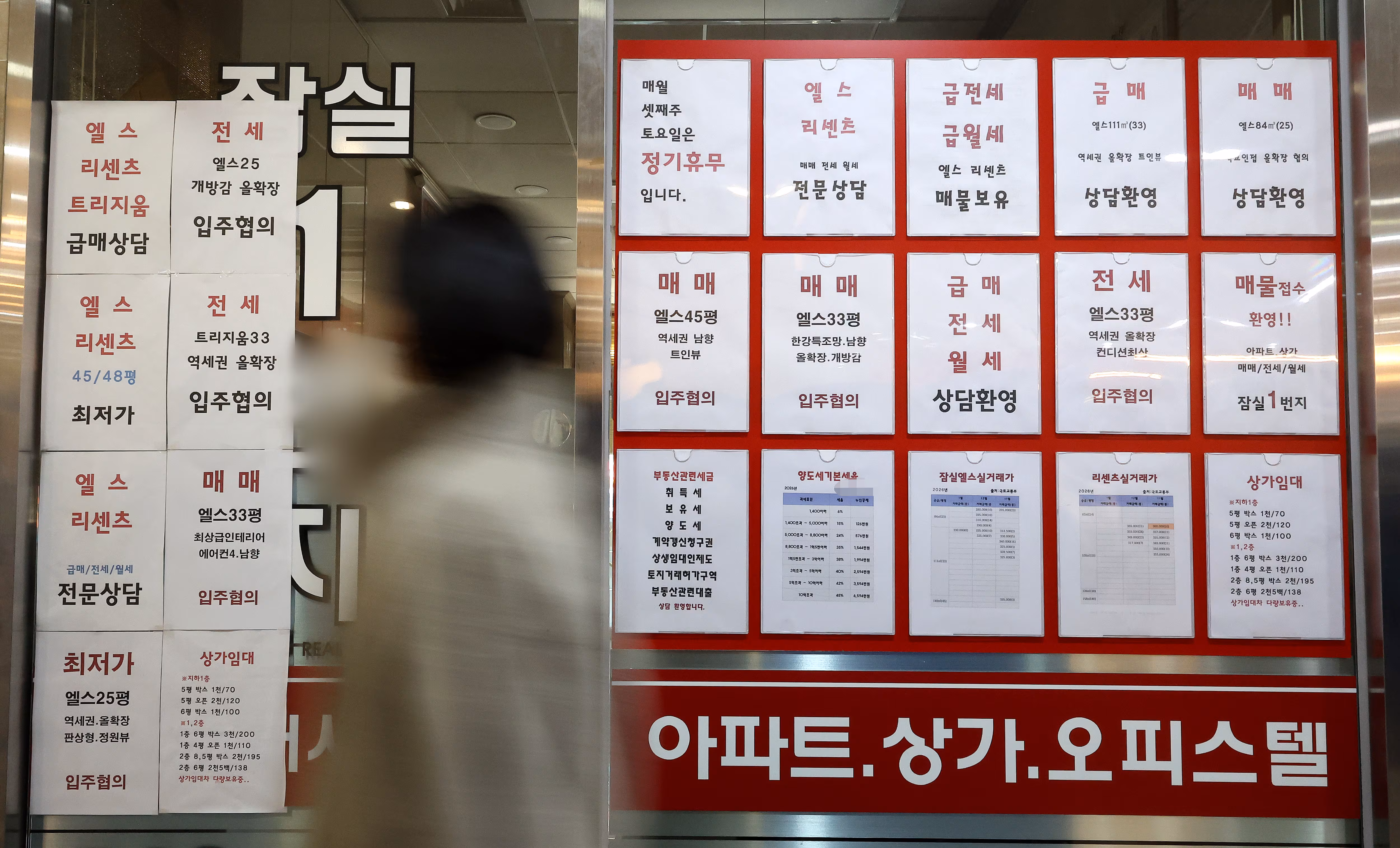 서울 잠실에 있는 공인중개사 사무실 유리 벽에 부동산 관련 세금과 아파트 매매 물건 등의 안내문이 게시되어 있다. /연합뉴스 