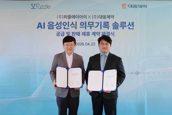 Kim Yong-sik, CEO of Puzzle AI (left), and Lee Chang-jae, CEO of Daewoong Pharmaceutical, are signing a supply agreement and posing for a commemorative photo / Provided by Daewoong