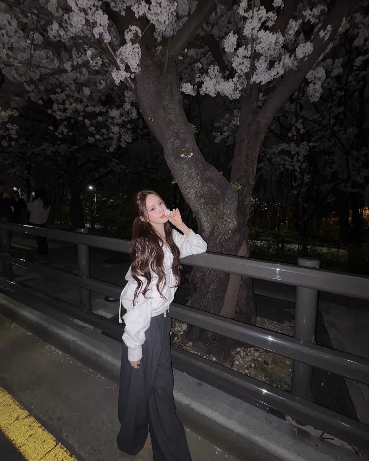 Close-up of white puff-shoulder zip-up hoodie + dark gray wide pants nighttime cherry-blossom styling / Photo = Izna Instagram (@izna_offcl)