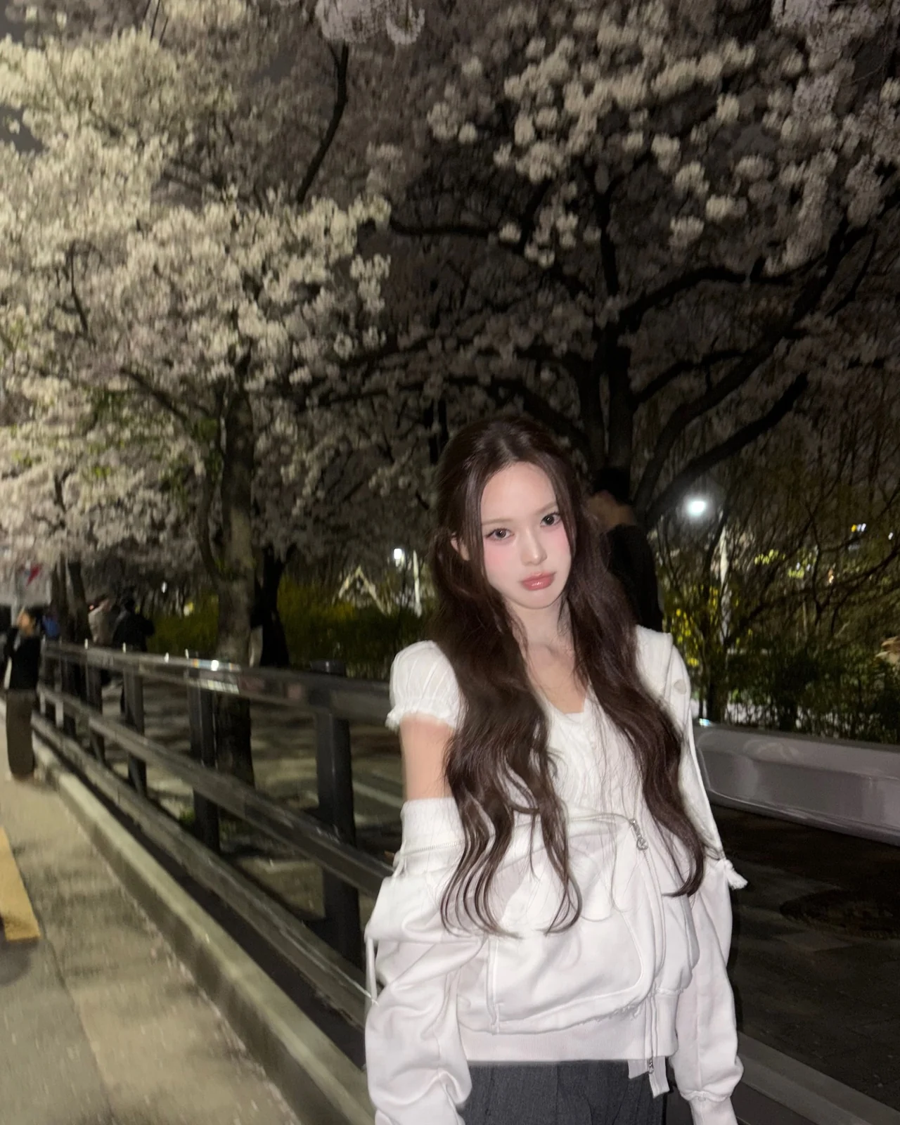 White zip-up hoodie with puff-shoulder detail + nighttime cherry-blossom background vibe / Photo = Izna Instagram (@izna_offcl)