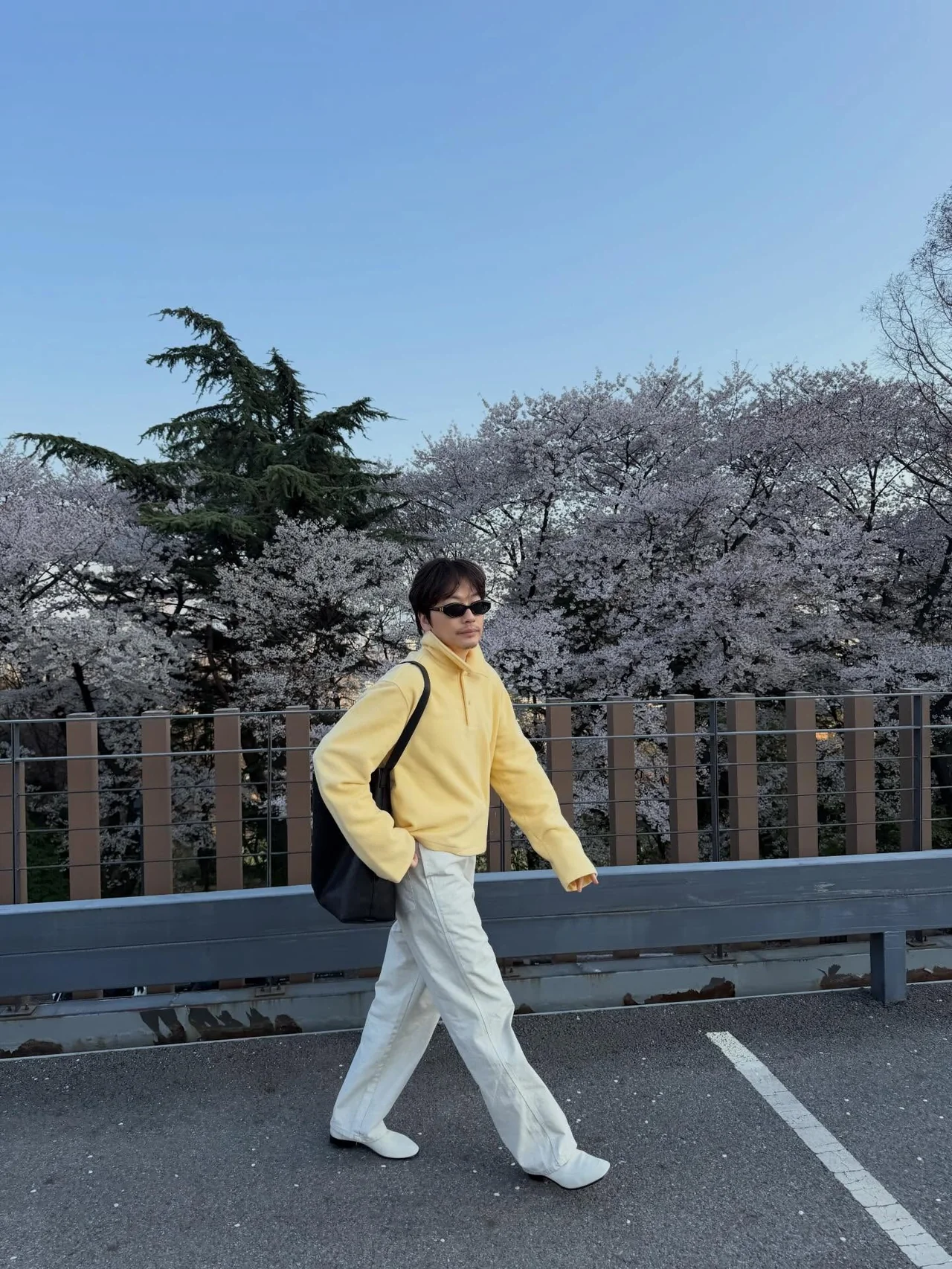 Yellow half‑zip fleece + ivory wide pants + white cowboy boots + black backpack — cherry blossom stroll look / Photo = Lee Dong‑hwi Instagram (@leedongwhee)