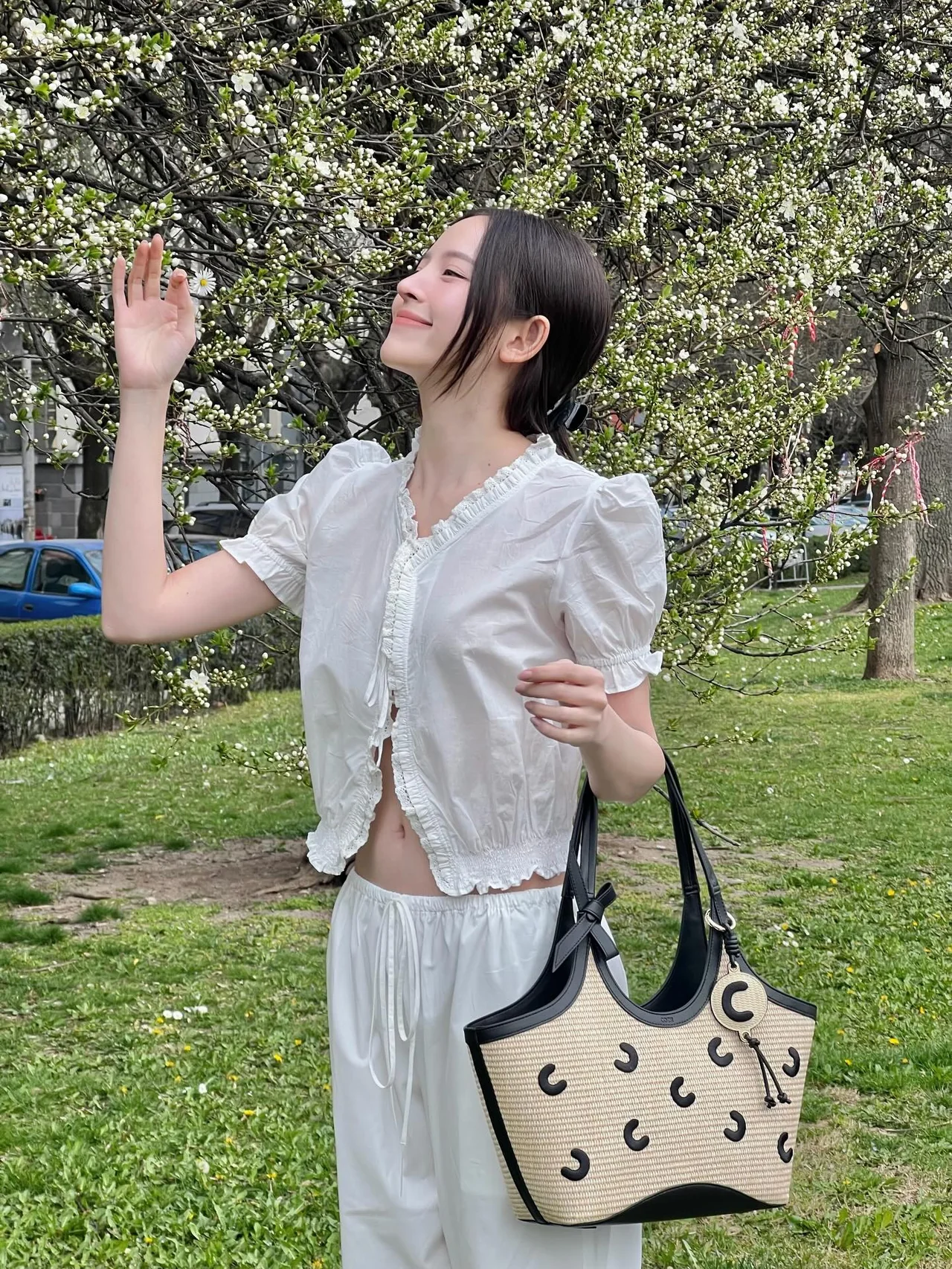 Spring daily look: white cotton crop blouse and wide pants set topped with a raffia basket bag. /Photo: Nuttanicha D. Instagram
