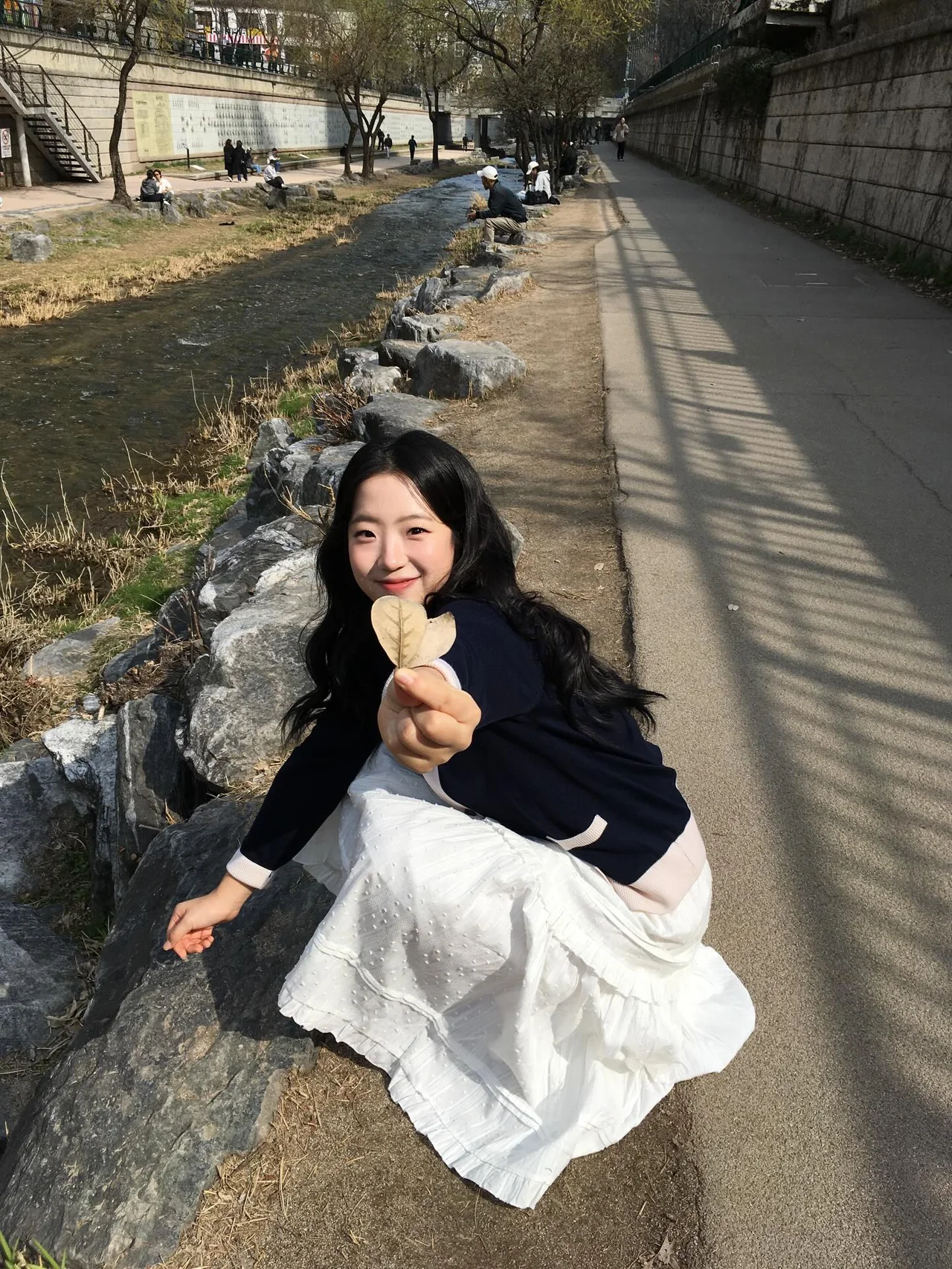 

<figure>” /><figcaption>
<figure></figcaption></figure>
<p><strong>ポイントはネイビーとホワイトの2トーンカーディガンだ</strong></p>
<p>今回のルックの主役はネイビーのVネックカーディガン。前立てのボタンラインと袖口、ポケットの縁にクリームホワイトのパイピングが入り、シンプルなネイビーカーディガンより格段に洗練されクラシックな印象を与える。胸の左側には小さなキツネの刺繍パッチがアクセントになり可愛らしさを添える。伝統的なプレッピーなムードが色濃いアイテムで、こうしたクラシックなカーディガンは流行に左右されにくく長く着られるのも利点だ。</p>
<figure><img decoding=