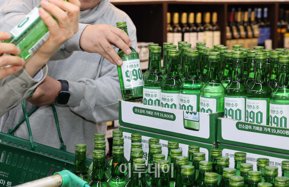 &nbsp;  On the 6th, customers at Danong Mart in Garak Market, Songpa-gu, Seoul, check out Good Soju 990 on display. The neighborhood-supermarket exclusive comes in a 360 ml (about 12.2 fl oz) bottle with 16% ABV. Sunyang Soju chairman Woong-rae Cho appears in the ads himself to cut marketing costs, letting the company pass savings into the price. The consumer price is 990 KRW (approximately $0.74) per bottle; a case of 20 sells for 19,800 KRW (approximately $14.85). (Intern reporter Ye-yeon Kim kimye@)