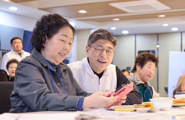 정재헌 SKT CEO가 지난달 27일 경기도 포천시 관인노인대학에서 어르신 고객의 스마트폰을 살펴보고 대화를 나누는 모습. [사진: SKT]