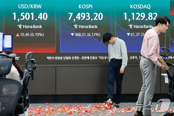 Traders clean up confetti celebrating the KOSPI surpassing 8,000 for the first time during intraday trading before plunging below the 7,500 level at the close at the dealing room of Hana Bank headquarters in Seoul on May 15, 2026. / Courtesy of News1