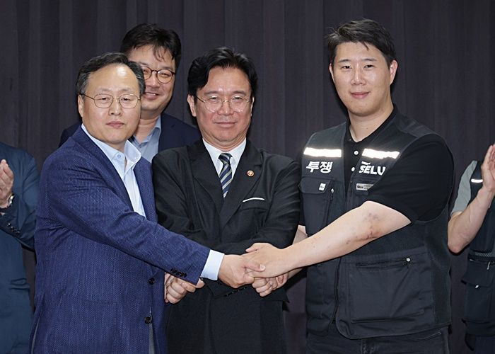 20일 밤 경기도 수원시 장안구 경기고용노동청에서 열린 삼성전자 임금협상을 마친 후 여명구 삼성전자 디바이스솔루션(DS·반도체 사업 담당) 피플팀장(왼쪽)과 최승호 삼성그룹 초기업노동조합 삼성전자지부 위원장(오른족)이 잠정 합의안에 서명한 후 김영환 고용노동부 장관과 손을 맞잡고 있다. ⓒ연합뉴스