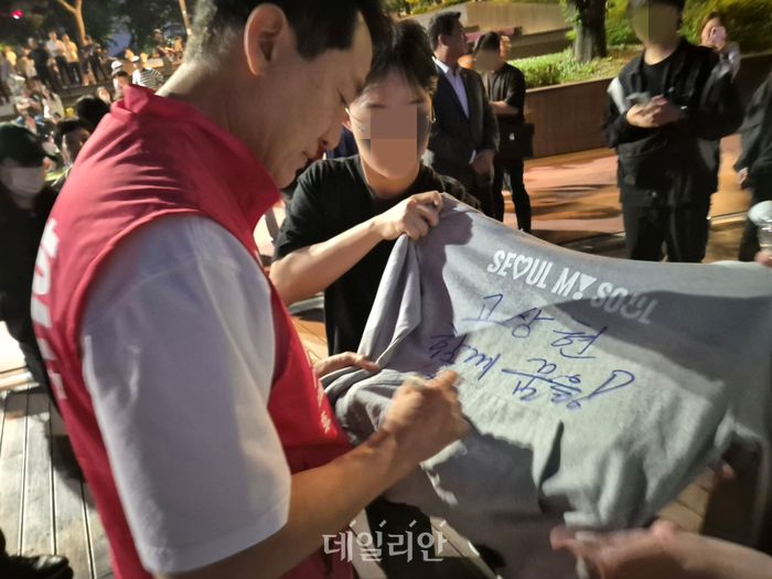 오세훈 국민의힘 서울시장 후보가 23일 송파구 잠실동 석촌호수에서 한 청년의 요청에 서울시 공식 후드티에 사인을 하고 있다. ⓒ데일리안 김주훈 기자