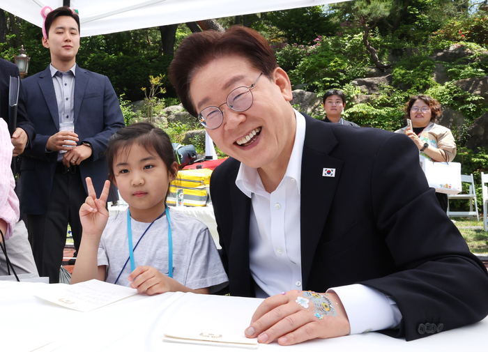 이재명 대통령이 5일 청와대 녹지원에서 열린 어린이날 초청행사에서 참석 어린이에게 사인 후 기념촬영을 하고 있다. 연합뉴스
