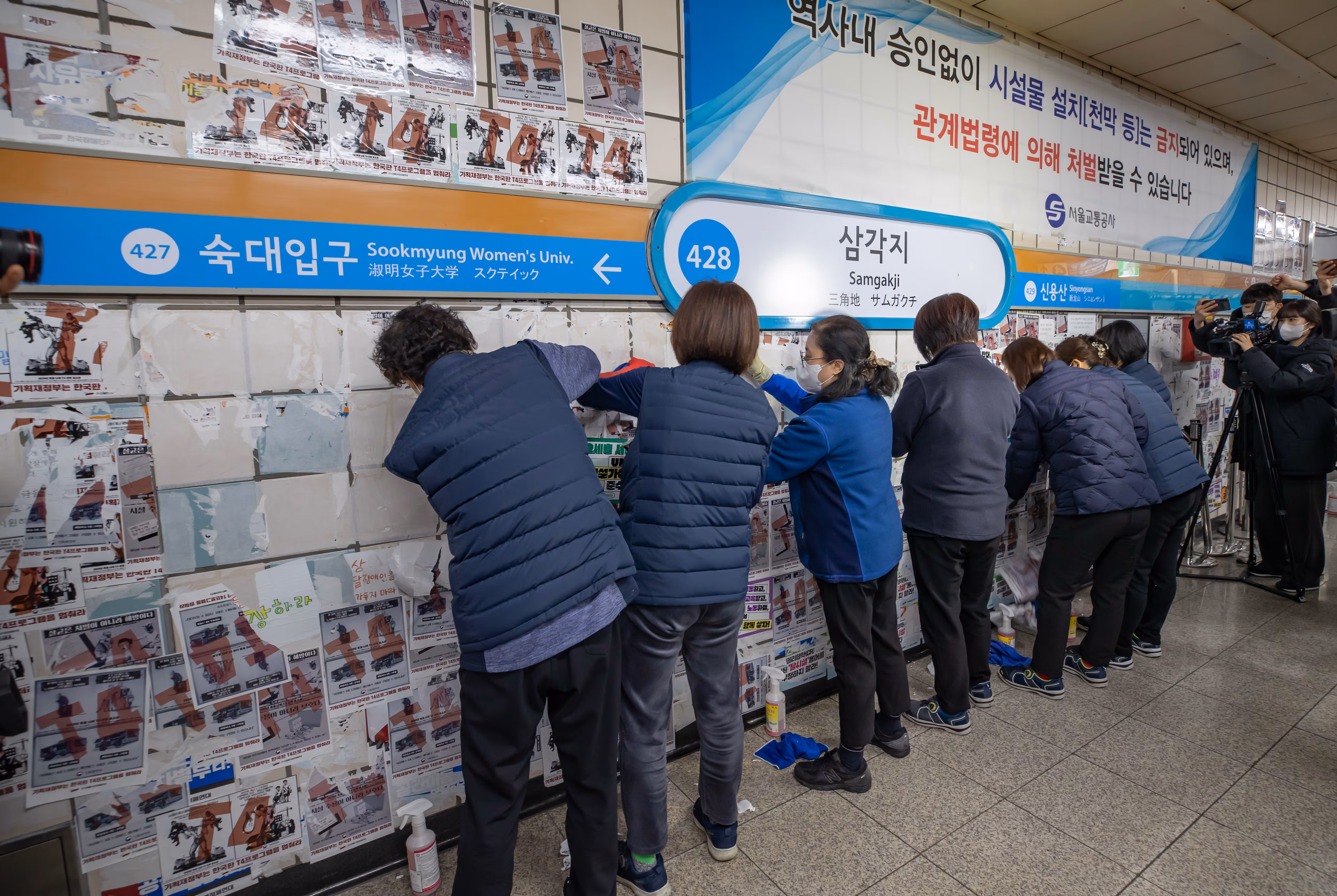 2023년 2월 27일 지하철 4호선 삼각지역 승강장에서 청소 노동자들이 전장연이 부착한 스티커를 떼는 작업을 하고 있다. /조선DB