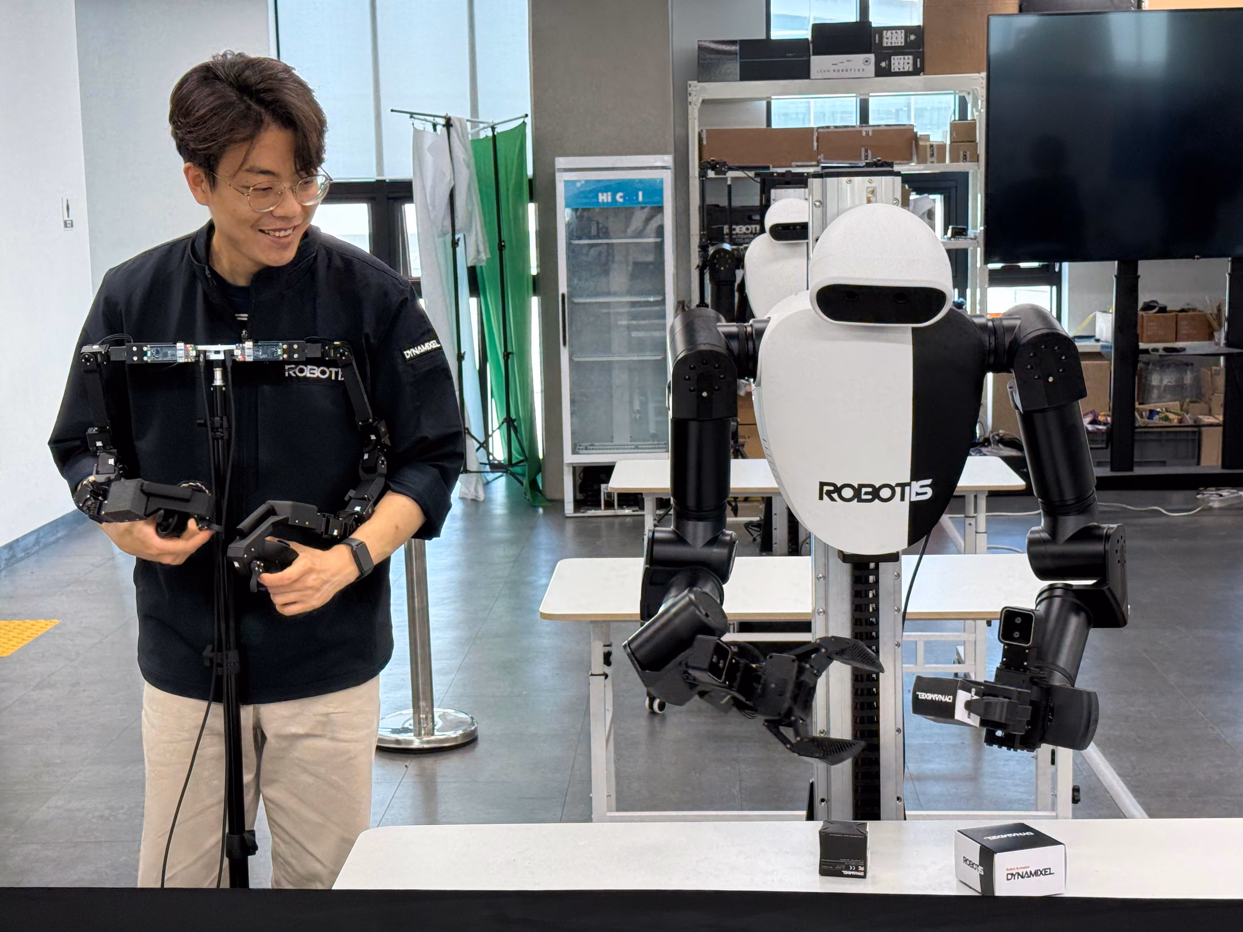 로보티즈 연구원이 외골격 형태의 리더암을 착용하고 움지기며 휴머노이드 로봇 'AI 워커'를 훈련하고 있다./로보티즈 제공