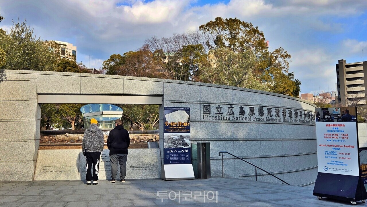 ‘8시 15분’을 상징하는 시곗바늘 조형물을 보고 있는 여행객/사진-투어코리아