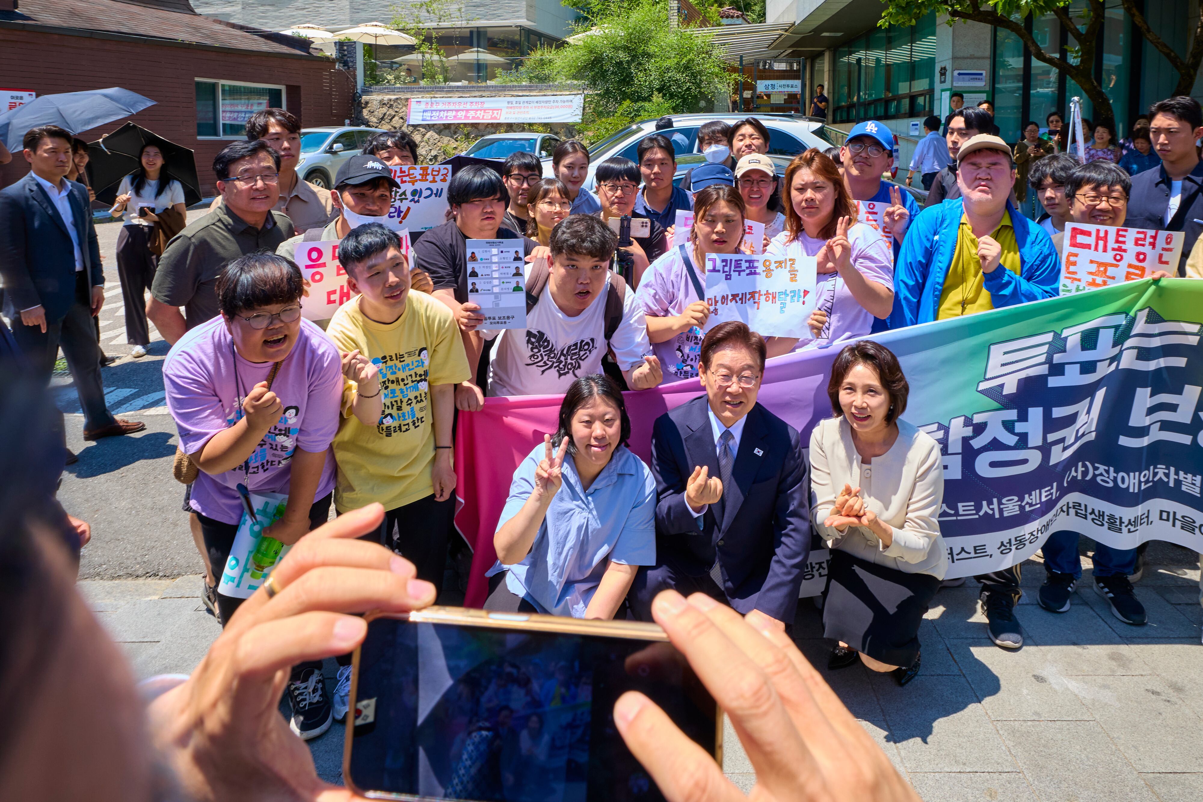 이재명 대통령과 김혜경 여사가 지난달 29일 제9회 전국동시지방선거 사전투표를 하기 위해 서울 종로구 삼청동 주민센터에 마련된 투표소로 향하며 발달장애인 투표 참정권 보장을 촉구하는 시민단체와 기념촬영을 하고 있다. /청와대 제공