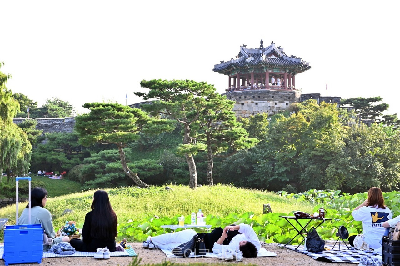 나들이객들이 수원화성 방화수류정이 보이는 용연에서 가을 피크닉을 즐기고 있다./사진-수원시