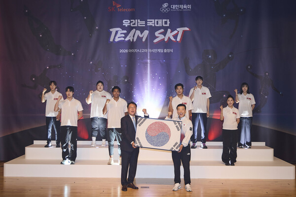 Team SKT 출정식에서 권영상 SKT Comm지원실장(왼쪽)이 김택수 진천선수촌장(오른쪽)에게 국민응원 태극기를 전달하고 Team SKT 선수단과 기념 사진을 촬영하는 모습 /SKT
