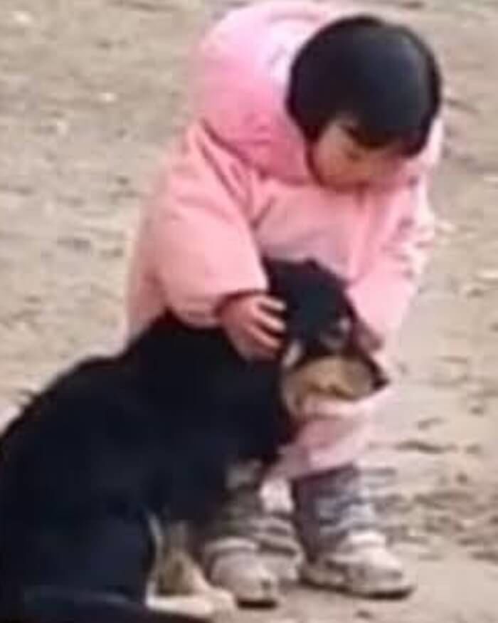 검은 개 가까이 몸을 숙인 어린 소녀
