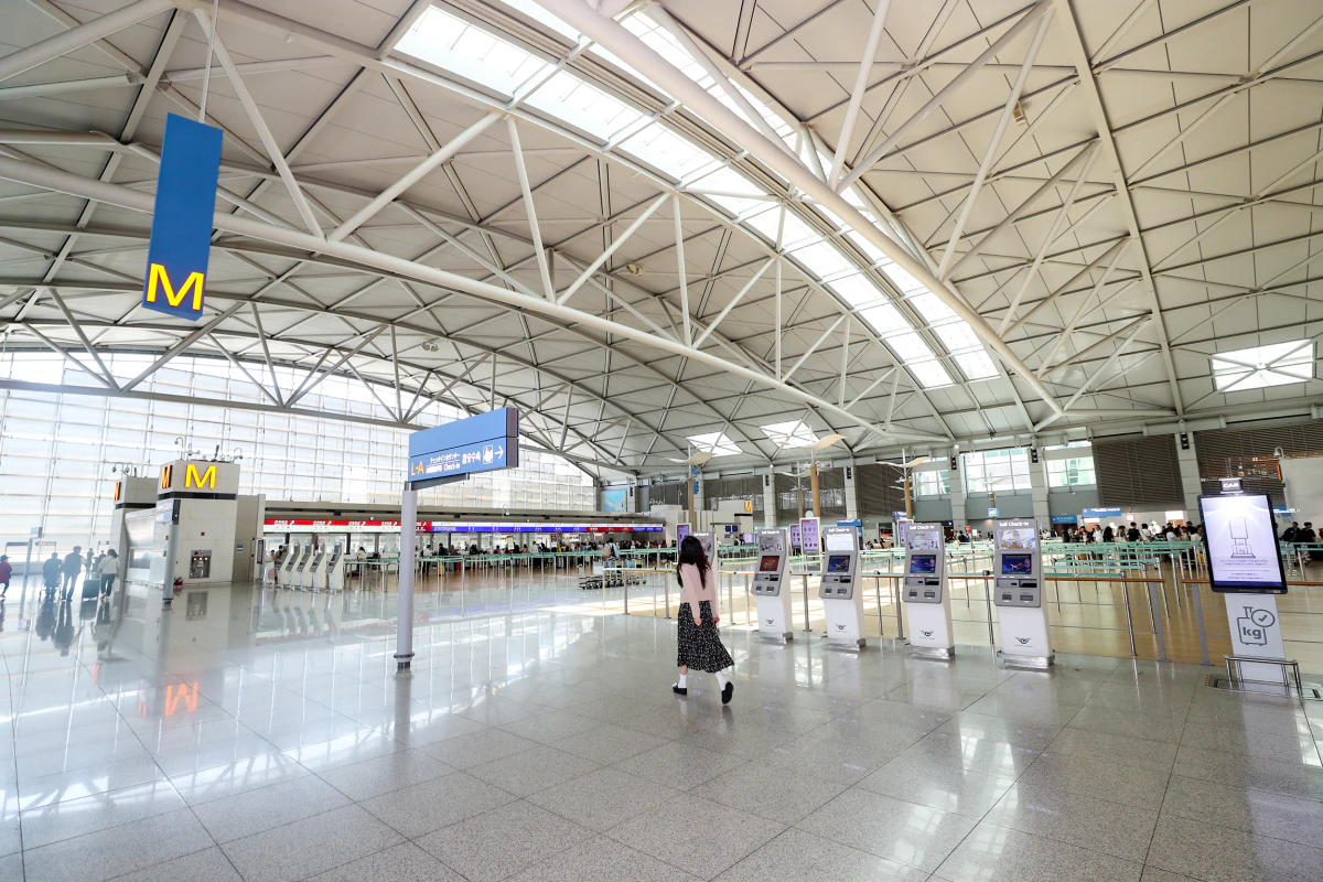인천공항 출국장 체크인 카운터와 셀프 체크인 키오스크 앞을 걷는 여행객
